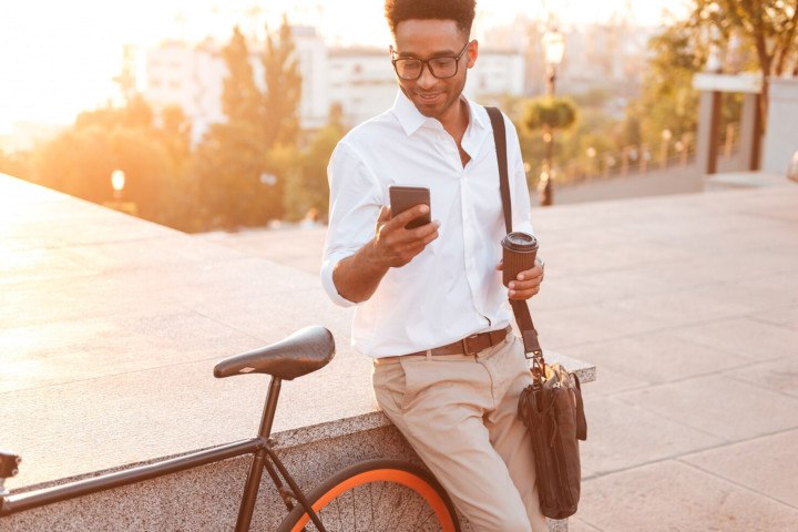 User playing on a smartphone with bicycle and coffee